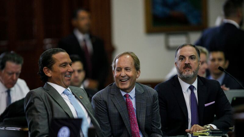 Texas Attorney General Ken Paxton, center, sits between defense attorneys Tony Buzbee, left,...