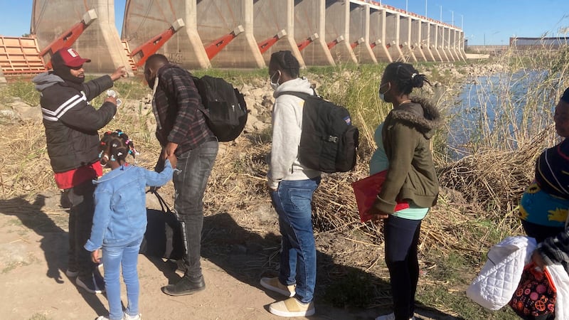 FILE - A Mexican smuggler guides a Haitian family across the Morelos Dam over the Colorado...